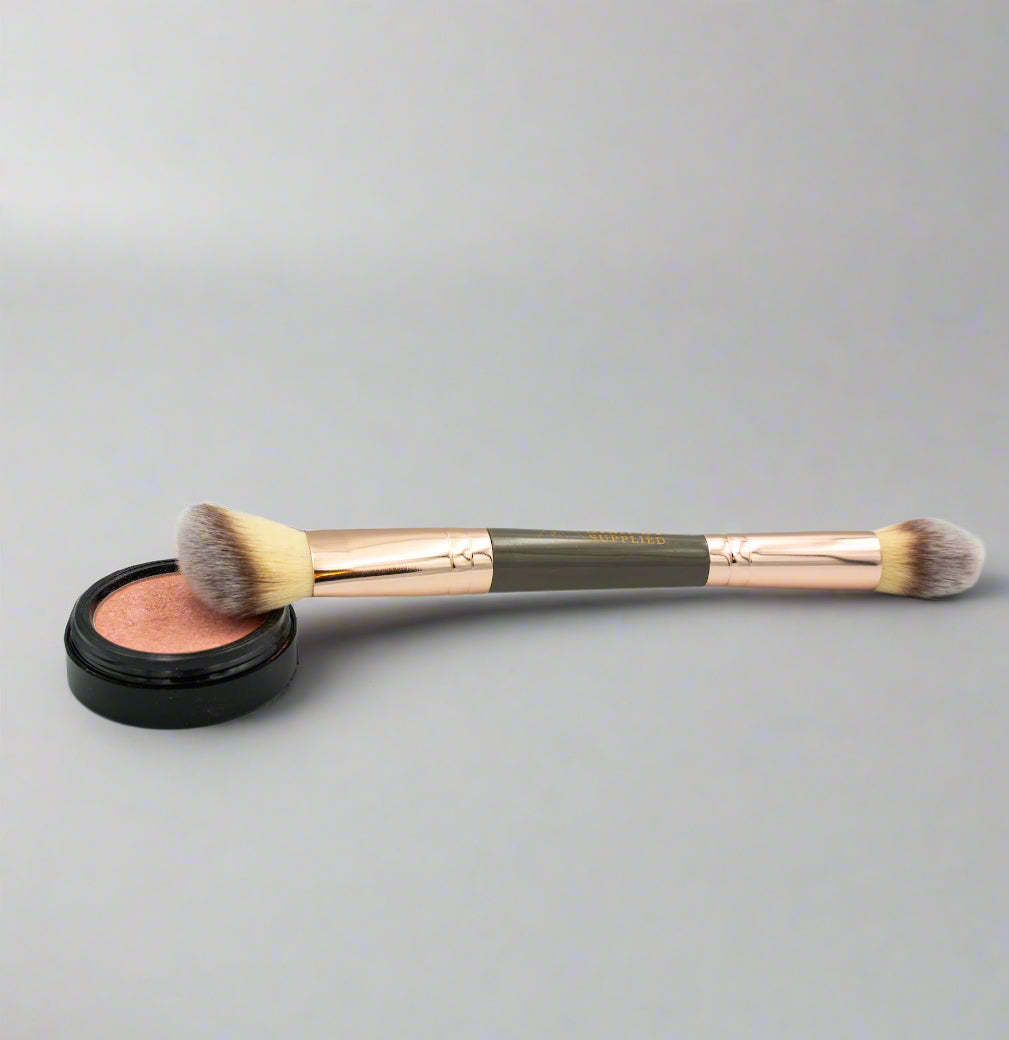 Makeup brush with pink blush on a gray background