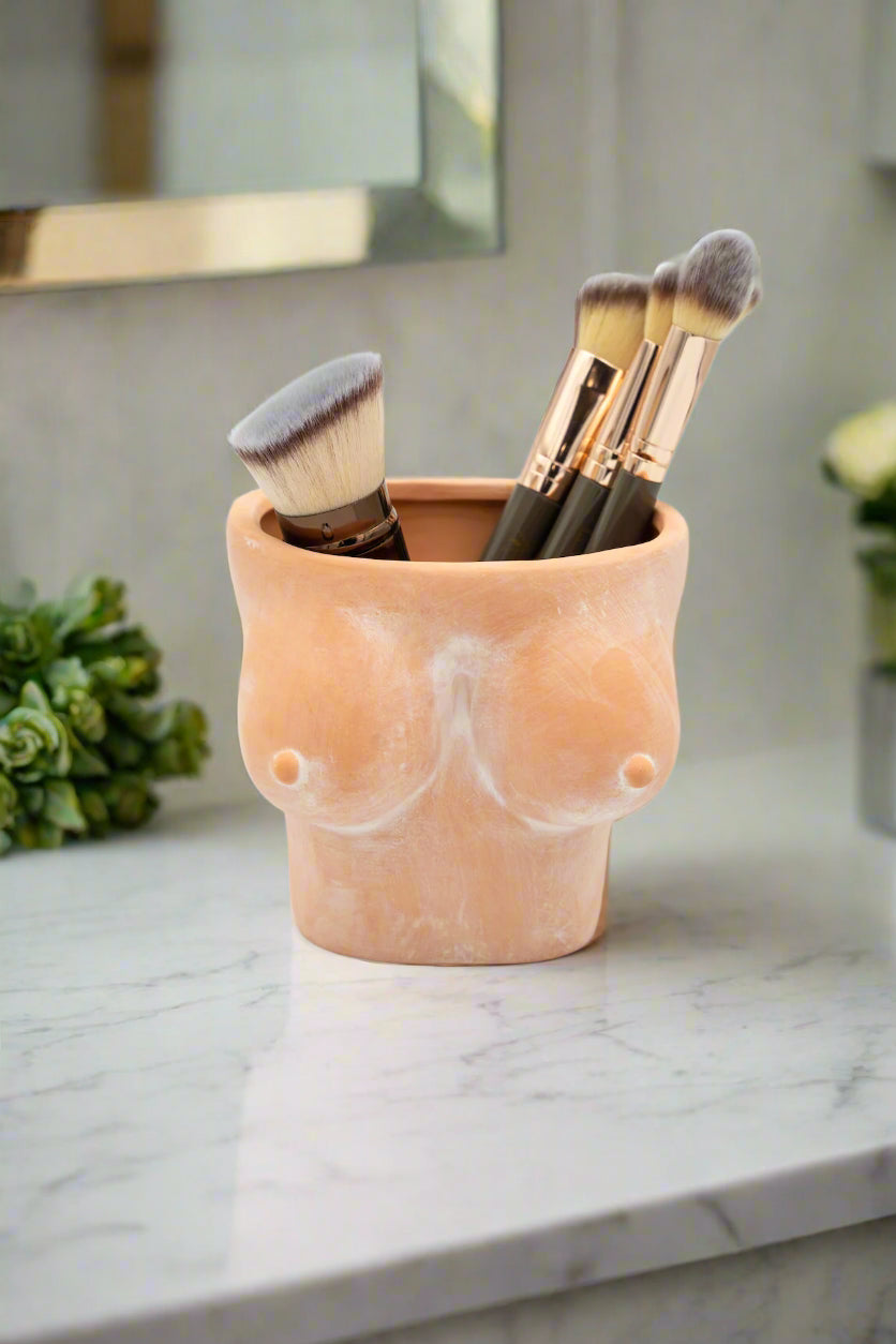 Ceramic cup with makeup brushes on a light background
