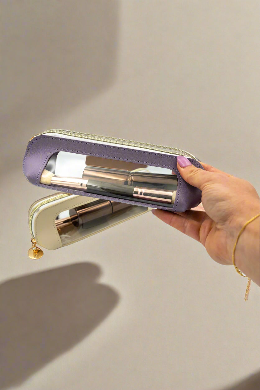Hand holding a purple and gold cylindrical product against a white background