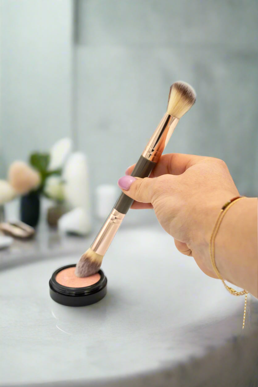 Makeup brush being dipped into a compact powder on a white background