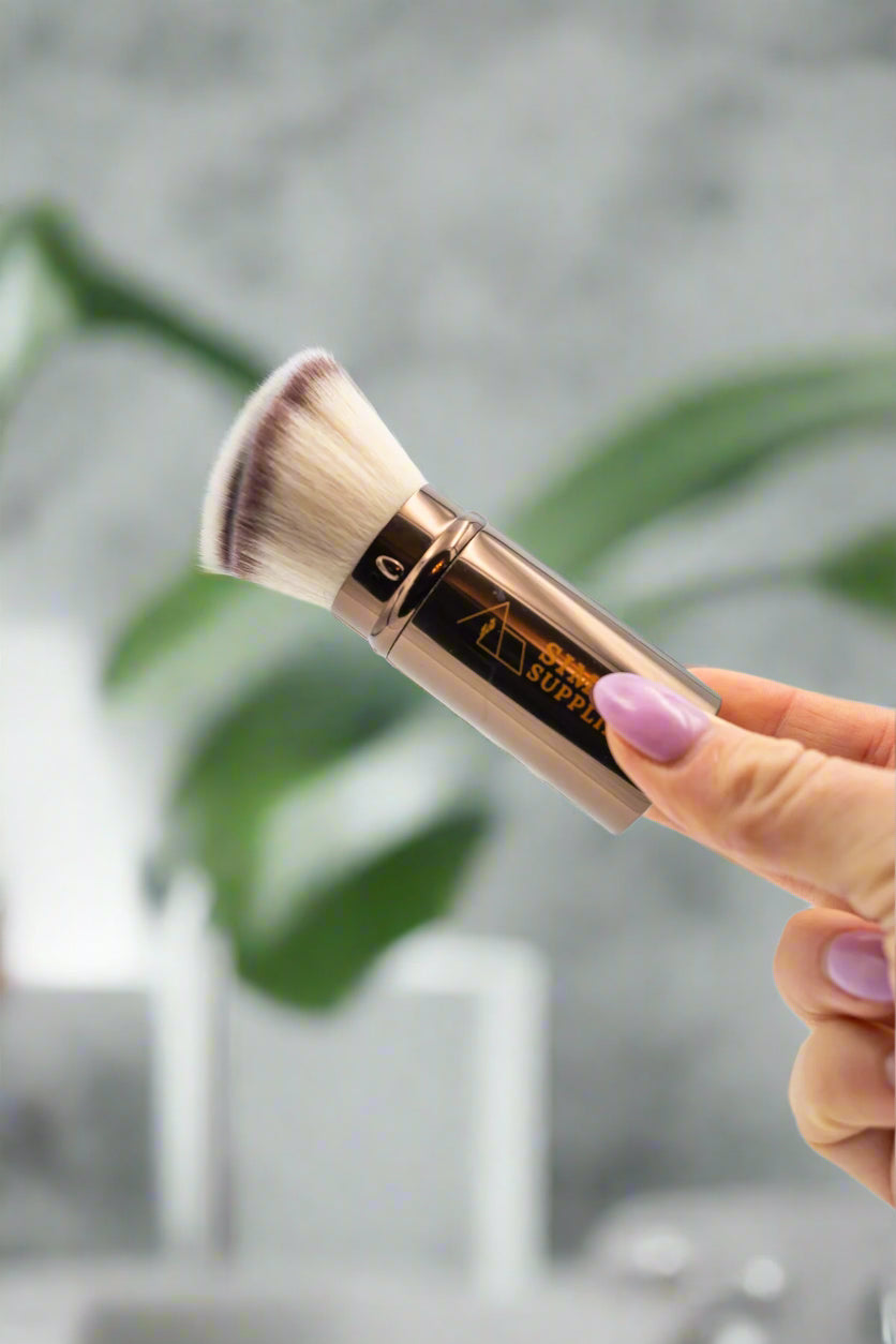 Makeup brush held by a hand with a blurred background